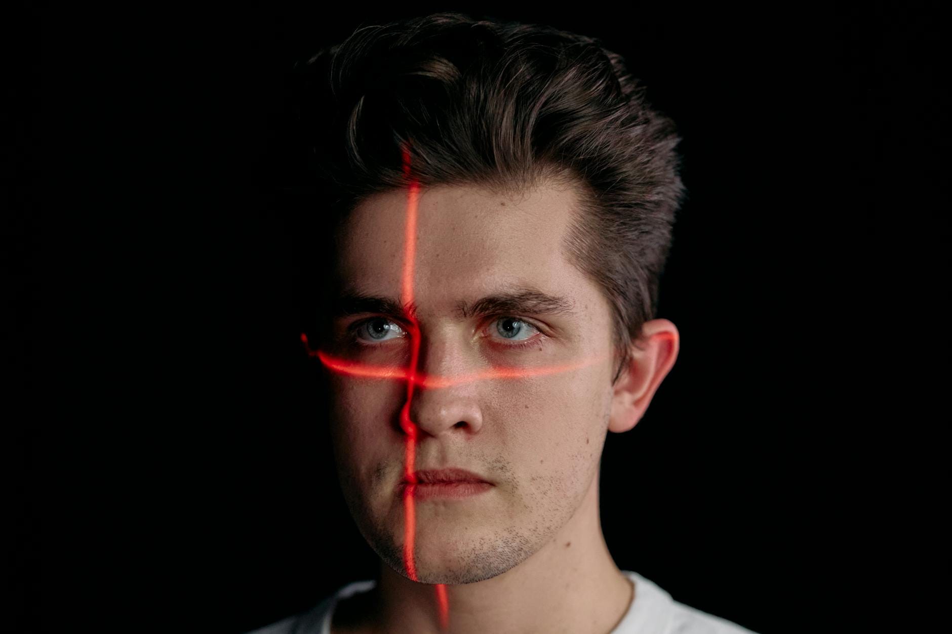 Twarz skanowana wiązkami laserowymi na czarnym tle