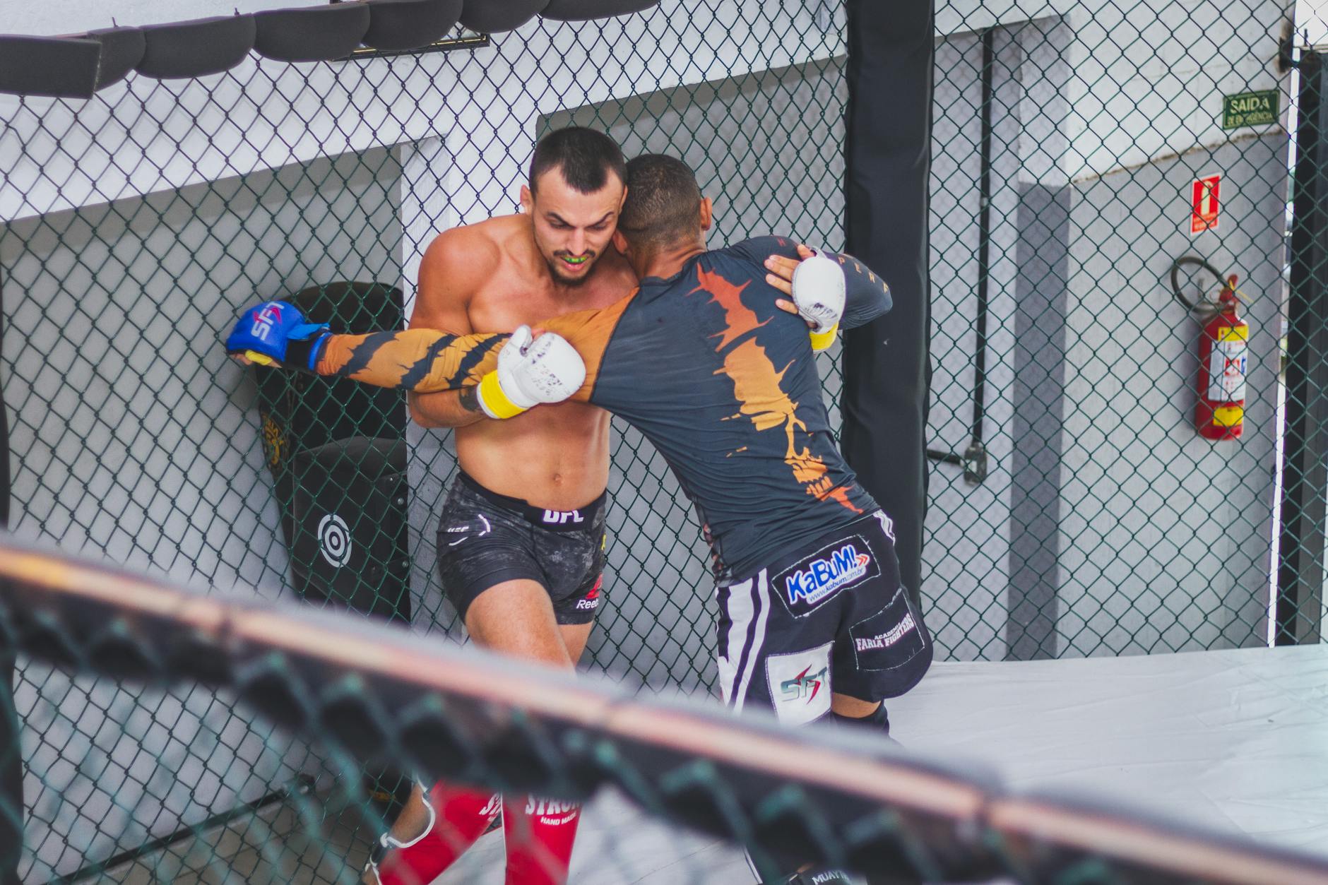 Dwóch mężczyzn walczy w ringu MMA, pokazując siłę i zwinność Dwóch mężczyzn walczy w ringu MMA, pokazując siłę i zwinność