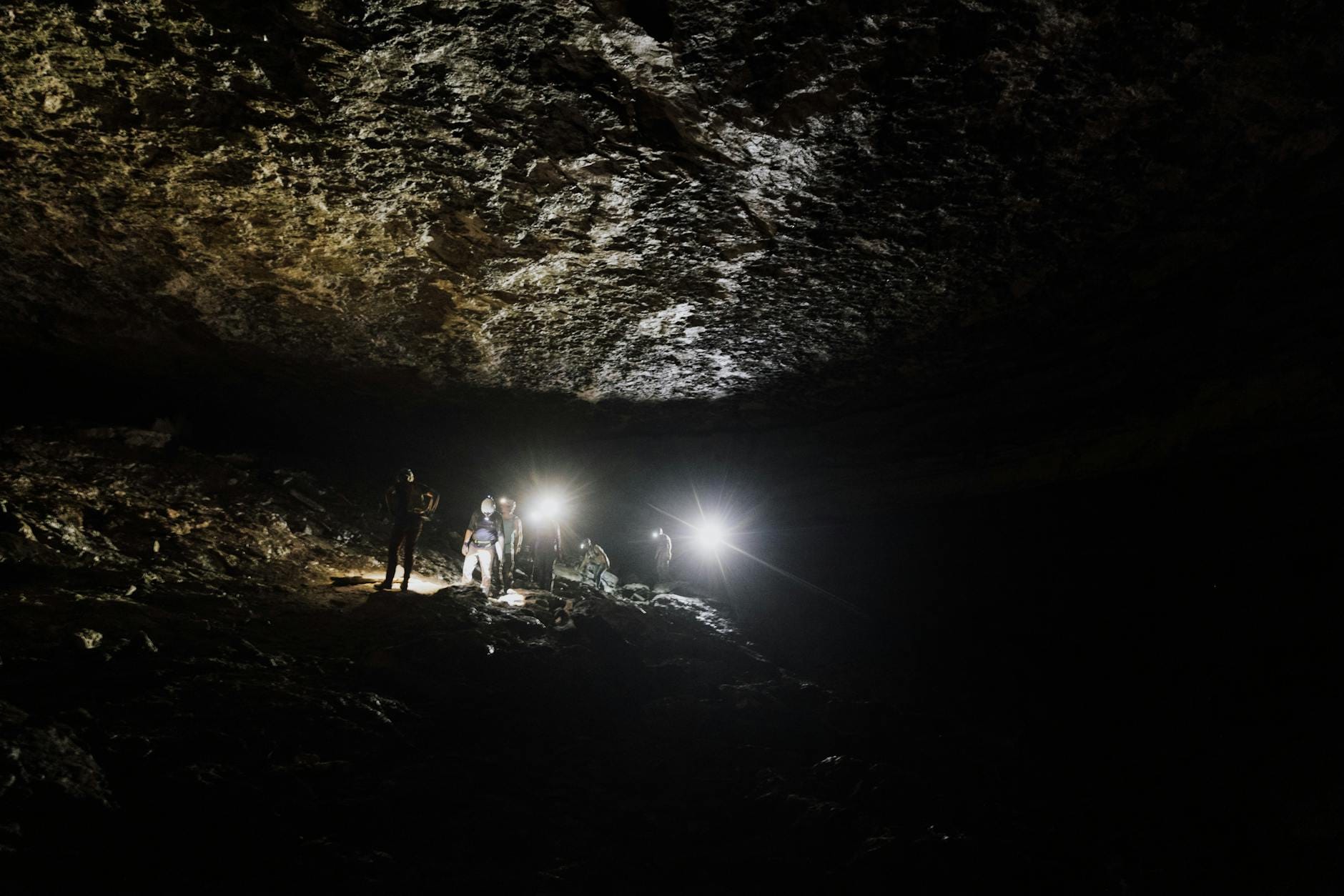 Grupa speleologów z latarkami eksploruje ciemną jaskinię