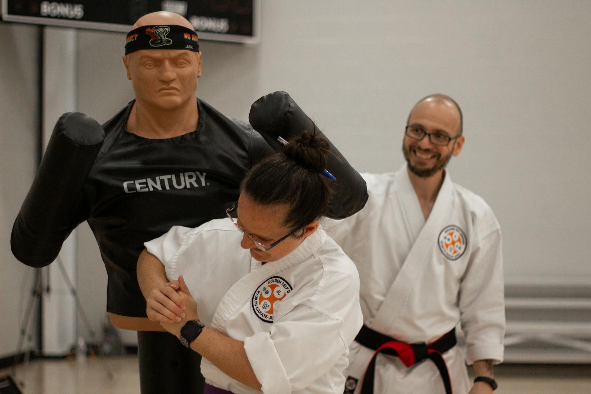 Instruktor uczy ucznia prostych technik samoobrony na manekinie karate