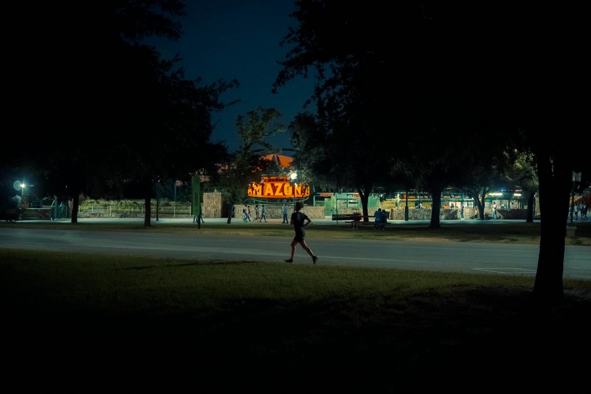 Samotna biegaczka biegnie nocą przez słabo oświetlony park