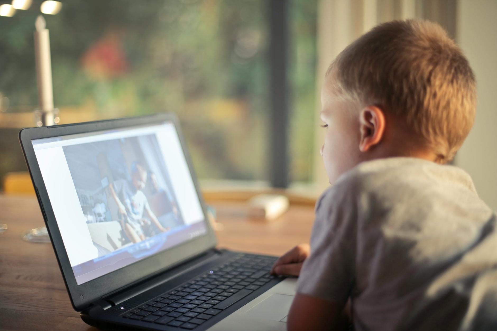 Chłopiec wpatrzony w ekran laptopa w pokoju w domowym zaciszu