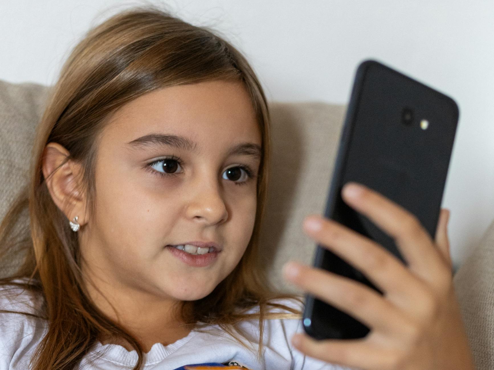 Uśmiechnięta nastolatka korzysta z telefonu w domu