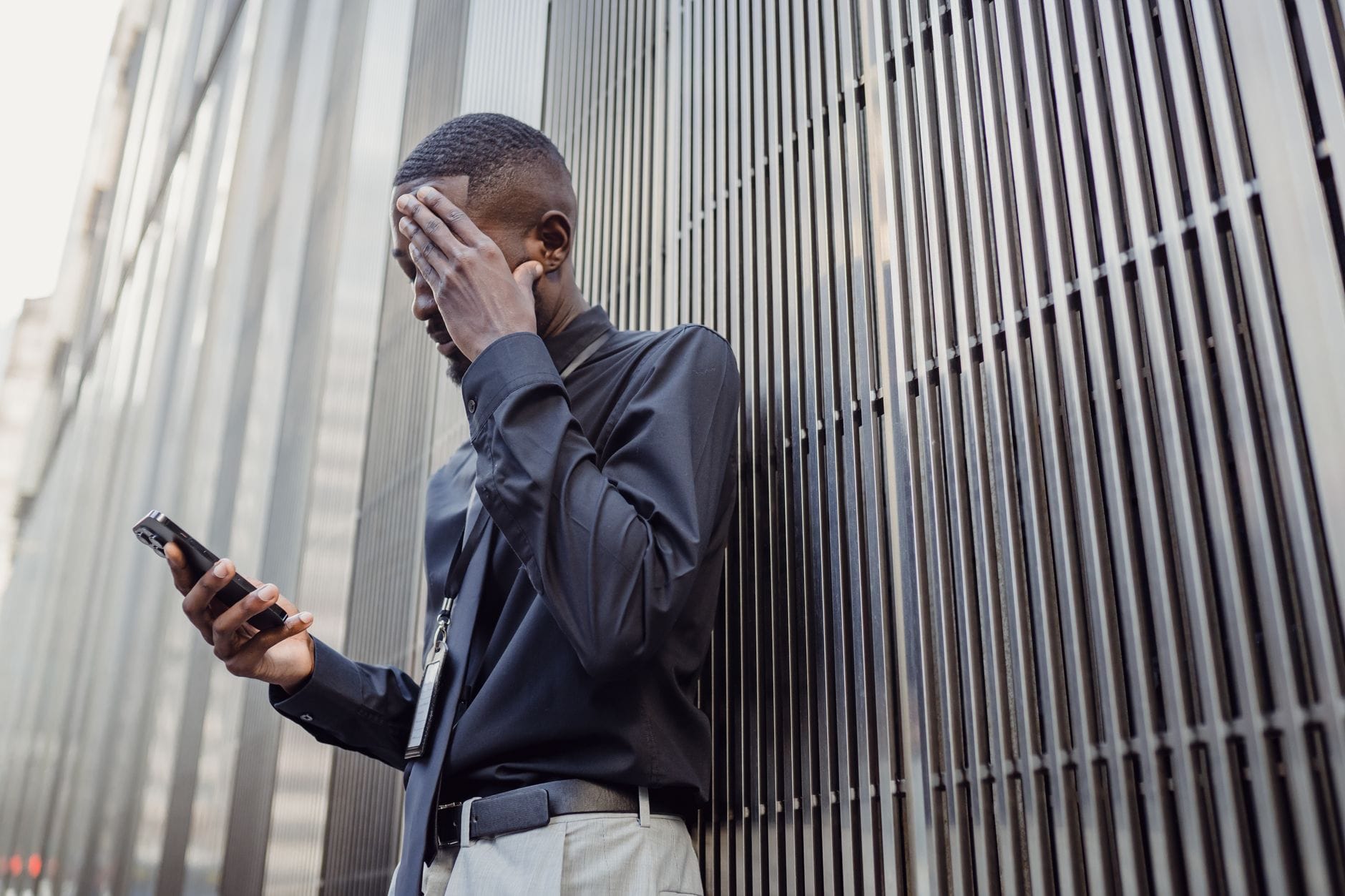 Jak zachować spokój po kradzieży telefonu: blokady, zgłoszenia i odzyskanie kont Zaniepokojony mężczyzna w garniturze patrzy w smartfon przed biurowcem